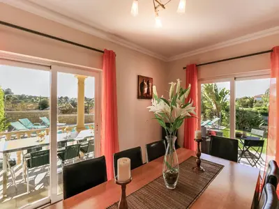 a dining room with a table with a vase of flowers at Luxury Holiday Villa Alegria Galé Beach, Albufeira in Albufeira