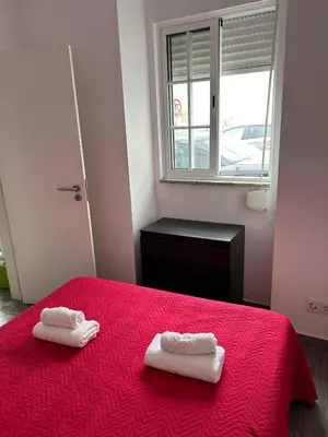 a bedroom with two towels on a red bed at Casinha in Faro