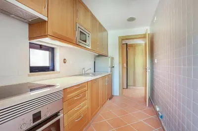 a kitchen with wooden cabinets and a tile floor at Golf F5 by Garvetur in Vilamoura