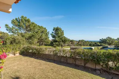 a garden with a stone wall and trees and a pool at Villa Costa by Gabi Miguel in Albufeira