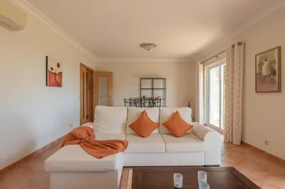 a living room with a white couch with orange pillows at Villa Costa by Gabi Miguel in Albufeira
