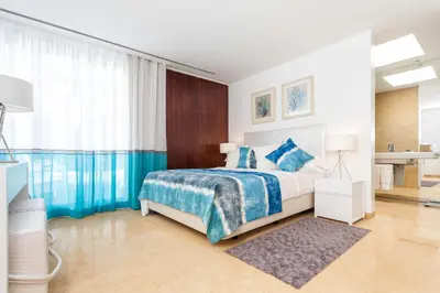 a bedroom with a bed with a blue and white blanket at Pine Cliffs Village in Albufeira