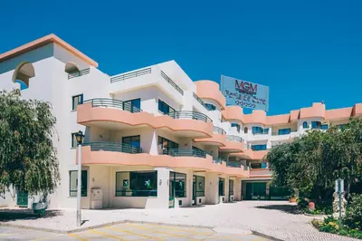 a hotel with a swimming pool with chairs and umbrellas at Grand Muthu Forte Da Oura in Albufeira
