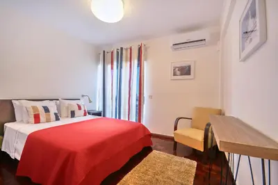 a bedroom with a bed with a red blanket and a chair at In Faro with Sea View in Faro