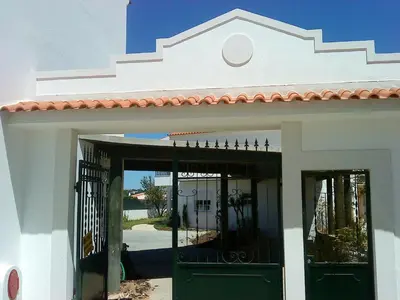 a white building with green doors and a gate at Charming Apartment in Albufeira, 60 m², Mountain View in Albufeira