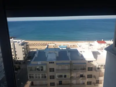 a view of a building and the beach from a window at Vista Mar in Quarteira