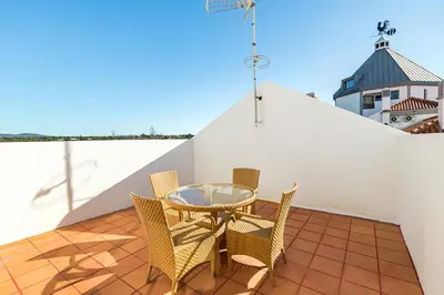 a patio with a glass table and chairs on a roof at Algardia Marina Parque by Garvetur in Vilamoura