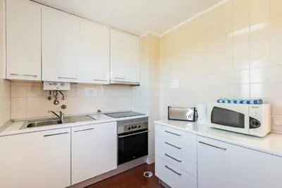a kitchen with white cabinets and a sink and a microwave at Algardia Marina Parque by Garvetur in Vilamoura