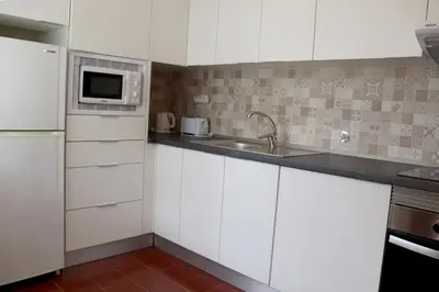 a kitchen with white cabinets and a sink and a microwave at Algardia Marina Parque by Garvetur in Vilamoura
