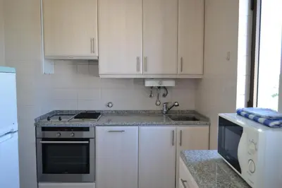 a kitchen with white cabinets and a stove top oven at Algardia Marina Parque by Garvetur in Vilamoura