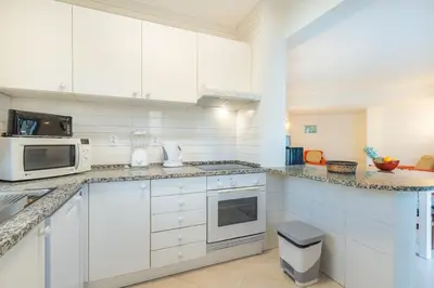 a kitchen with white cabinets and a microwave at Algamar by Garvetur in Vilamoura