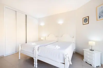 a white bedroom with a white bed and a white dresser at Algamar by Garvetur in Vilamoura