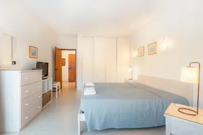 a white bedroom with a bed and a television at Algamar by Garvetur in Vilamoura
