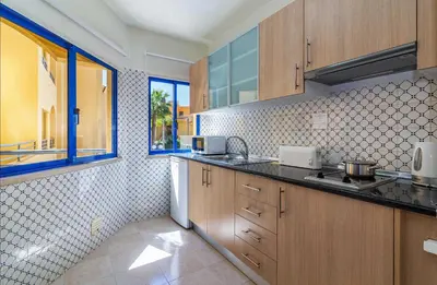 a kitchen with wooden cabinets and a window at Rio by Garvetur in Vilamoura