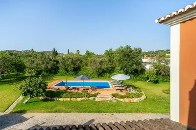 a pool in a yard with umbrellas and chairs at Quinta das Figueiras - Bordeira - Faro in Bordeira