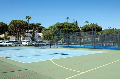 a tennis court with a parking lot with cars at Browns Sports Resort in Vilamoura