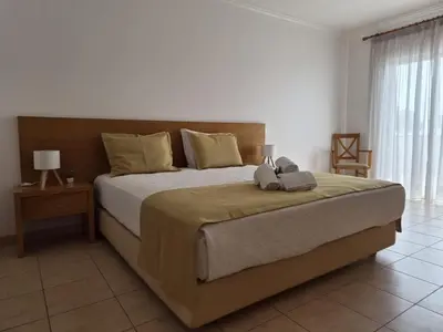 a bedroom with a bed with two blue pillows on it at Albufeira Mar Vilas in Albufeira