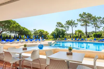 a patio with tables and chairs next to a swimming pool at Victory Village 3A in Quinta do Lago