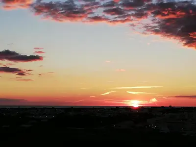 a sunset over a city with the sun in the sky at Sea View urban apartment in Faro