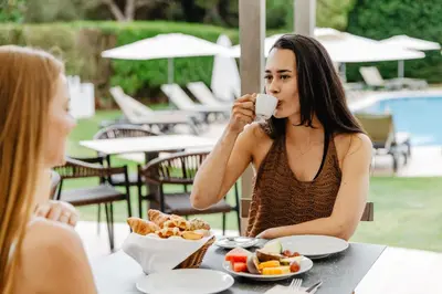 two women sitting at a table with a plate of food at Aqua Pedra Dos Bicos Design Beach Hotel - Adults Friendly in Albufeira