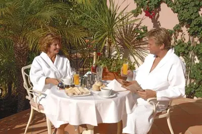 a man and a woman sitting at a table at Quinta Jacintina - My Secret Garden Hotel in Vale do Lobo