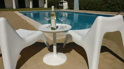 a table with two white chairs and a bottle of wine at Modern Pool Apartment, Vilamoura in Quarteira