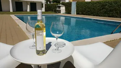 a bottle of wine and glasses on a table next to a pool at Modern Pool Apartment, Vilamoura in Quarteira