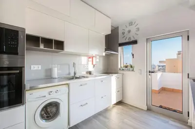 a kitchen with white cabinets and a washer and dryer at Maria Rita Faro Rooftop Apartment in Faro