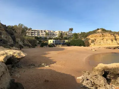 a sandy beach with a building on a mountain at magnifique appartement sur la plage ... in Albufeira