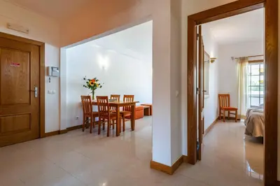 a dining room with a table and chairs and a bedroom at Apartamentos Monte da Vinha I in Albufeira