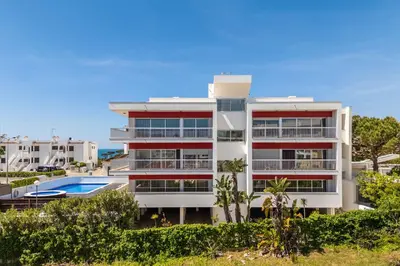 a white building with a swimming pool in front of it at Apartamentos Turisticos Monte da Vinha II in Albufeira