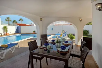 a dining room with a table and a swimming pool at Villa Francella- Relaxing holidays in an ideal location by DreamvillasAlbufeira in Albufeira