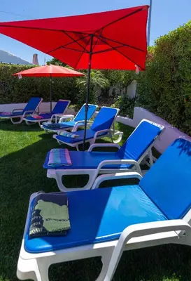 a row of beach chairs with a red umbrella at LOTUS VILLA, Albufeira in Albufeira