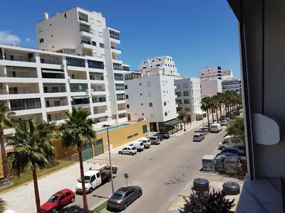 a view of a street with parked cars and buildings at Apartment Girasol Front Beach Quarteira Algarve in Quarteira