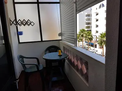 a small table and chair in front of a window at Apartment Girasol Front Beach Quarteira Algarve in Quarteira