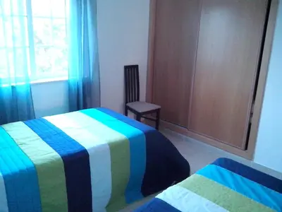 a bedroom with two beds and a chair and a window at Spacious apartment in Albufeira 80 m² with shared pool in Roja- Pé