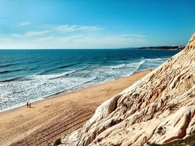 a sandy beach with people walking on it next to the ocean at Welcoming apartment in Albufeira 60 m² with shared pool in Albufeira
