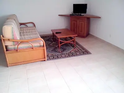 a living room with a chair and a table and a tv at Welcoming apartment in Albufeira 60 m² with shared pool in Albufeira