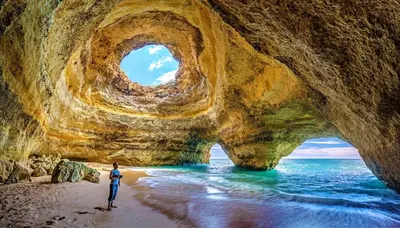 a man standing on a beach in front of a cave at Charming apartment with shared pool in Albufeira - 60 m² in Albufeira