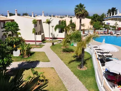 a view of a resort with a pool and palm trees at magnifique maison en resort près des plages in Albufeira