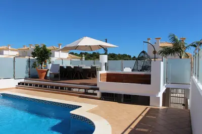 a villa with a swimming pool and an umbrella at magnifique et spacieuse villa avec piscine privative in Albufeira