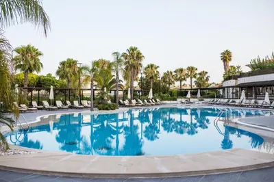 a pool with wicker chairs and a table with two cocktails at Wyndham Grand Algarve in Quinta do Lago