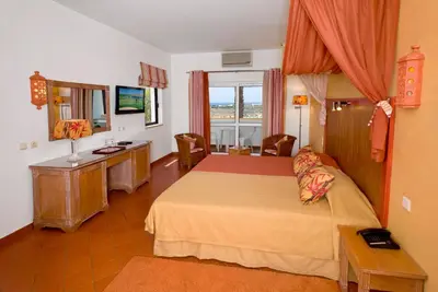 a bedroom with a bed and a desk and a television at Cerro Da Marina Hotel - Adults Only in Albufeira