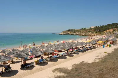 a beach with many umbrellas and a crowd of people at Apartamento com Piscina em Albufeira, Praia da Oura in Albufeira