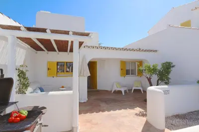 a white house with a patio with a table and chairs at Aldeia do Golf 151 - Clever Details in Vilamoura