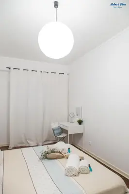 a white bedroom with a bed with towels on it at Palma's Place in Faro