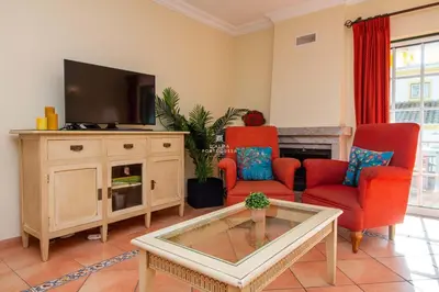 a living room with two red chairs and a tv at São Rafael Beach Villa- D´alma Rafaella in Albufeira