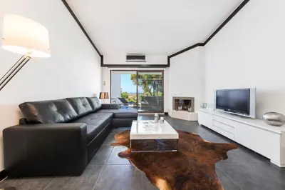 a living room with a black leather couch and a tv at Victory Village T1 & Mezzanine in Quinta do Lago