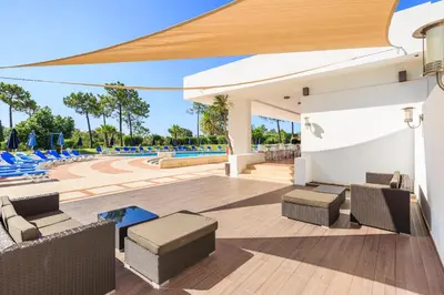 a patio at a resort with chairs and a pool at Victory Village T1 & Mezzanine in Quinta do Lago