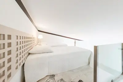 a white bedroom with a white bed and a window at Victory Village T1 & Mezzanine in Quinta do Lago